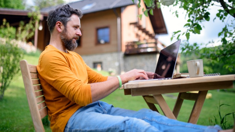 Caucasian male sitting outside with a laptop