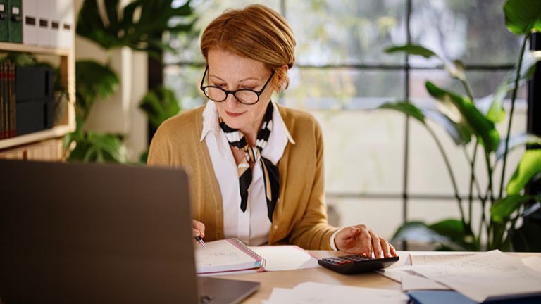 Professional women calculating finances at a desk with laptop and calculator